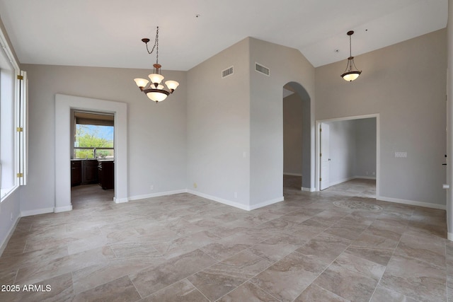 unfurnished room featuring baseboards, visible vents, arched walkways, and a notable chandelier