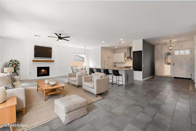 living room featuring a ceiling fan, visible vents, baseboards, recessed lighting, and a lit fireplace