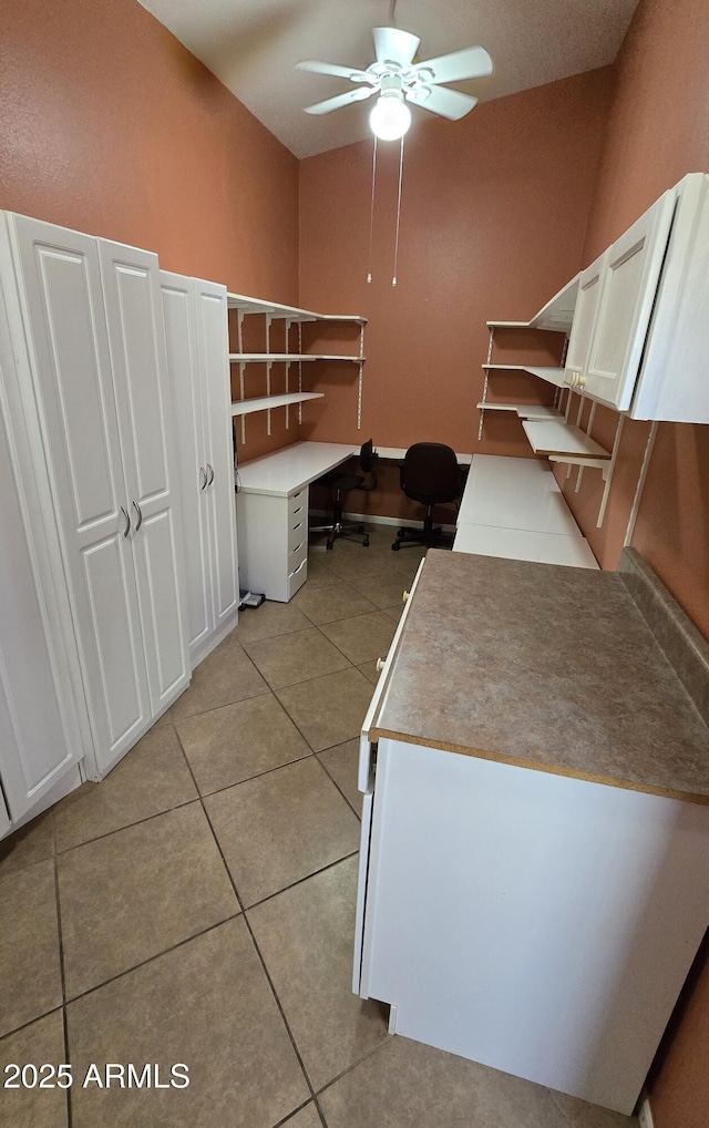 unfurnished office featuring ceiling fan, built in desk, and light tile patterned floors