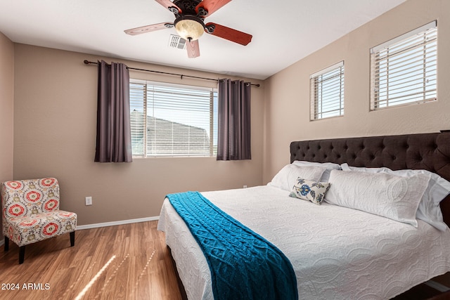 bedroom with hardwood / wood-style floors, multiple windows, and ceiling fan