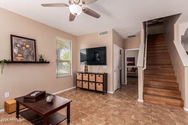 living room with stairs, a ceiling fan, baseboards, and light tile patterned floors