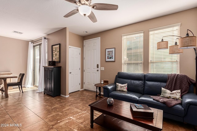living room featuring healthy amount of natural light, a ceiling fan, baseboards, and light tile patterned floors