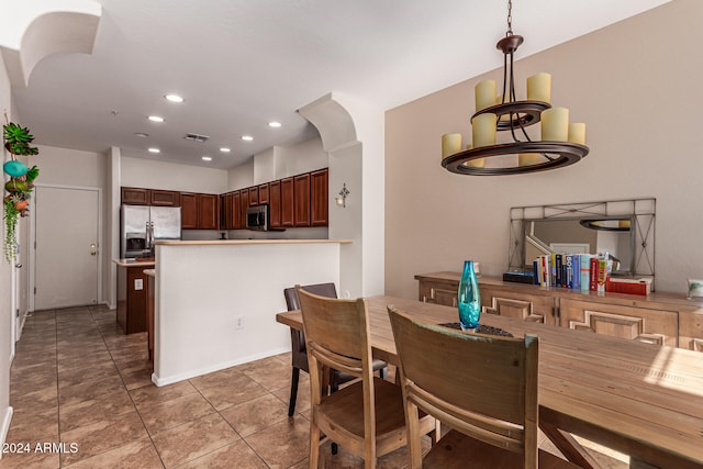 dining space with dark tile patterned flooring and an inviting chandelier