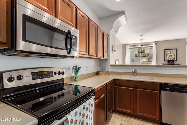 kitchen with light tile patterned flooring, appliances with stainless steel finishes, decorative light fixtures, sink, and kitchen peninsula