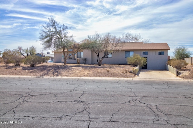 ranch-style home featuring driveway and stucco siding