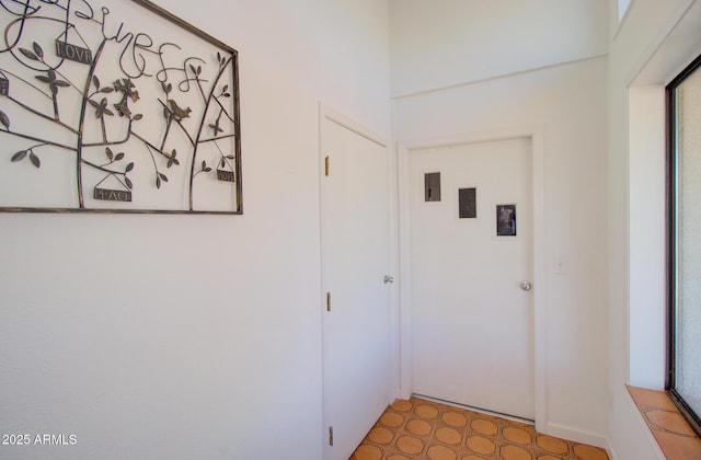 hallway featuring light floors and baseboards