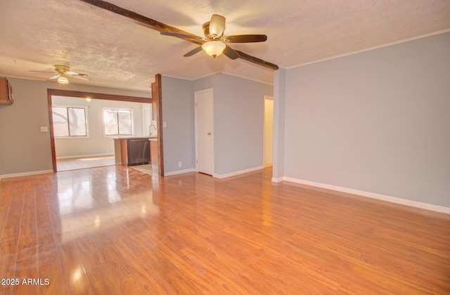 unfurnished living room with a textured ceiling, light wood finished floors, a ceiling fan, and baseboards