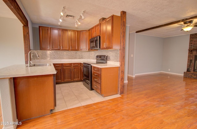 kitchen with electric range, visible vents, stainless steel microwave, a brick fireplace, and a sink