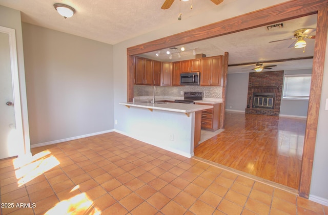 kitchen featuring stainless steel appliances, light countertops, decorative backsplash, open floor plan, and a peninsula