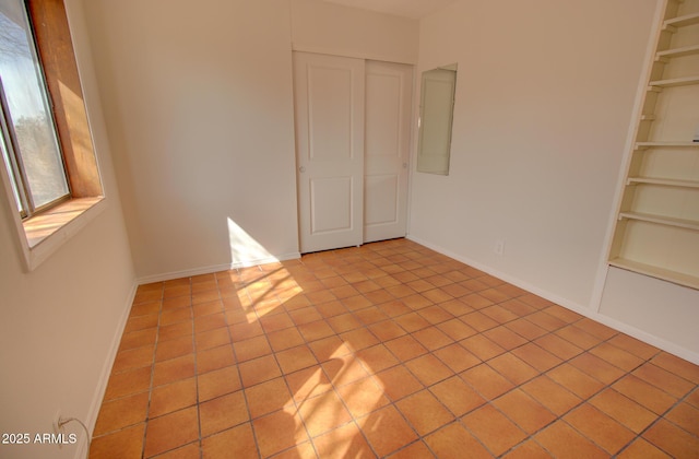 spare room with built in features, baseboards, and light tile patterned floors