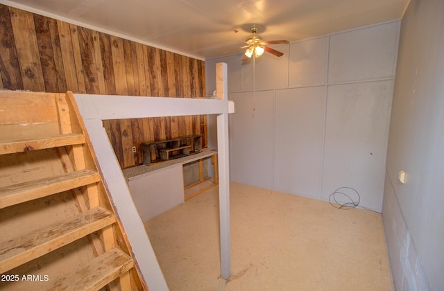 below grade area featuring wood walls and a ceiling fan