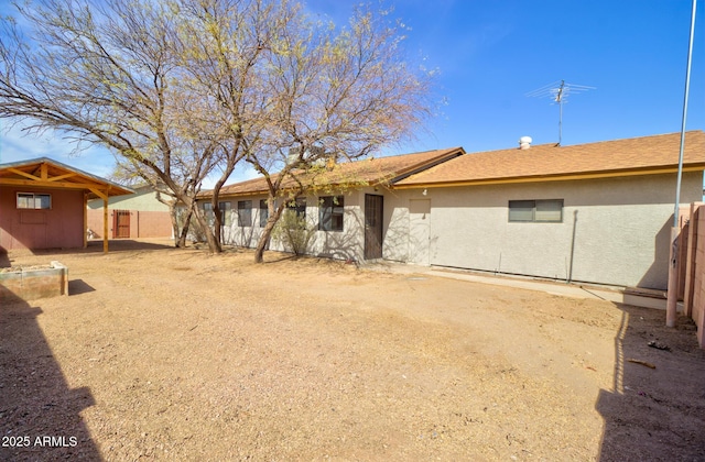 rear view of house featuring fence and stucco siding