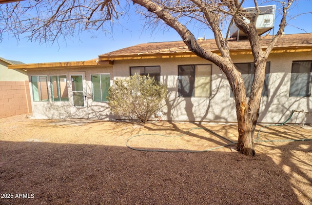 rear view of house with fence and stucco siding