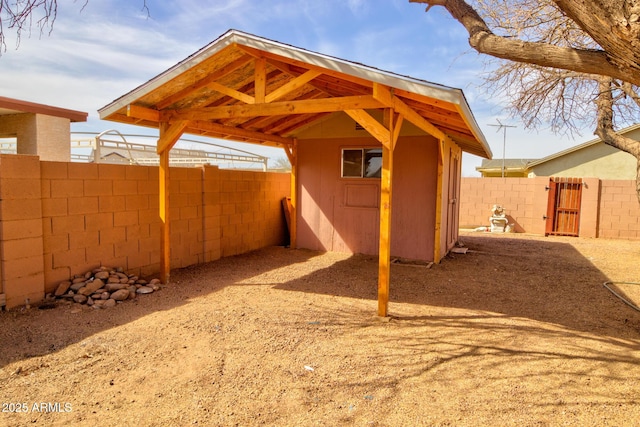 exterior space with a gate, an outdoor structure, a storage shed, and fence