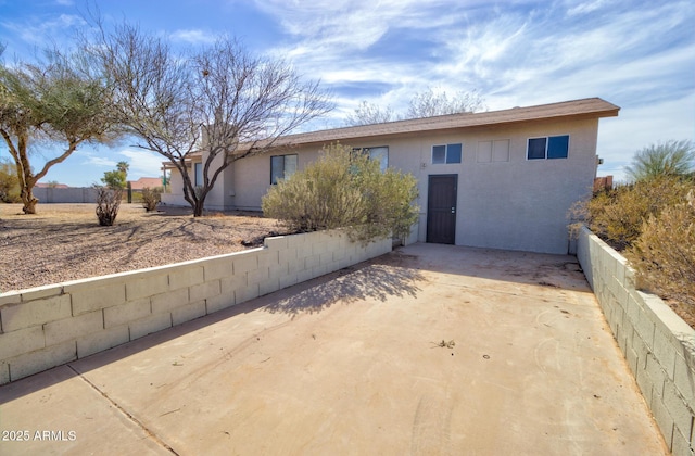 ranch-style house with fence, concrete driveway, and stucco siding