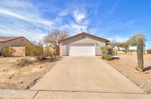 view of front of home with an attached garage, fence, concrete driveway, and stucco siding