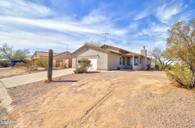 ranch-style home featuring a garage, fence, concrete driveway, stucco siding, and a chimney