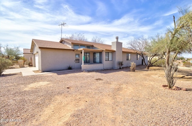 view of front of house with a garage, a chimney, and stucco siding