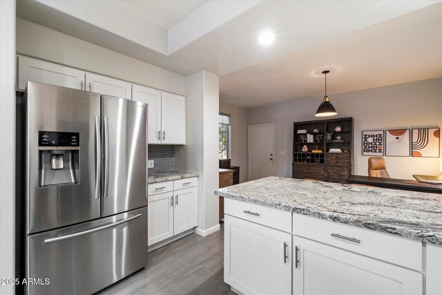 kitchen featuring stainless steel fridge, white cabinetry, decorative backsplash, and pendant lighting