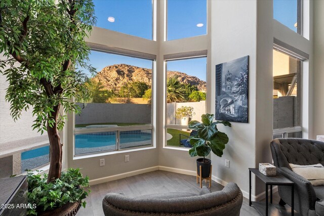 sitting room featuring a mountain view, wood finished floors, baseboards, and a high ceiling