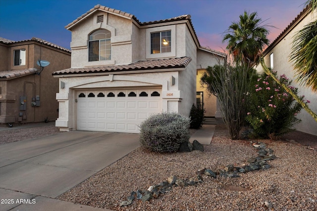 mediterranean / spanish home with stucco siding, driveway, an attached garage, and a tiled roof