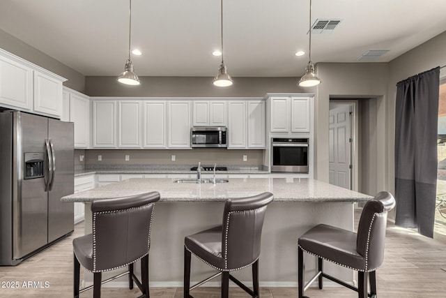 kitchen featuring appliances with stainless steel finishes, hanging light fixtures, white cabinetry, and sink