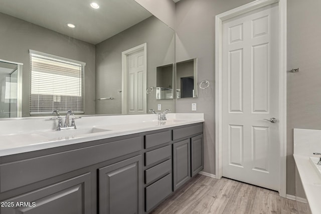 bathroom featuring wood-type flooring, vanity, and a tub