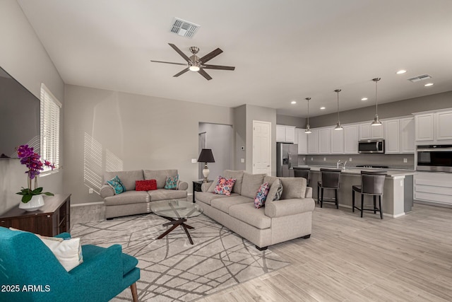 living room with ceiling fan and light hardwood / wood-style floors