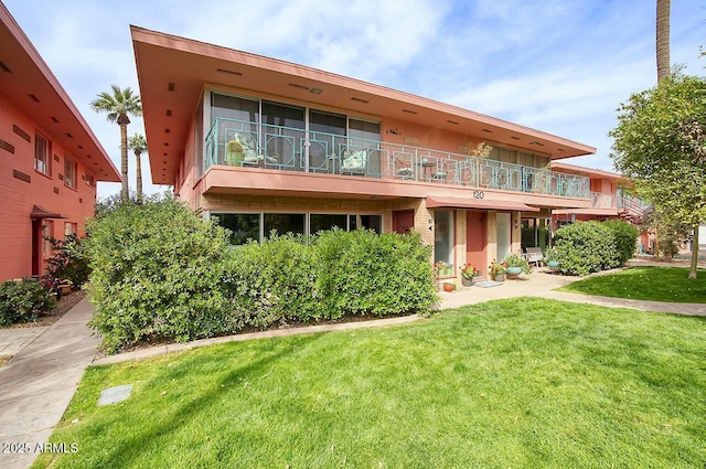 view of front of house with a balcony and a front lawn