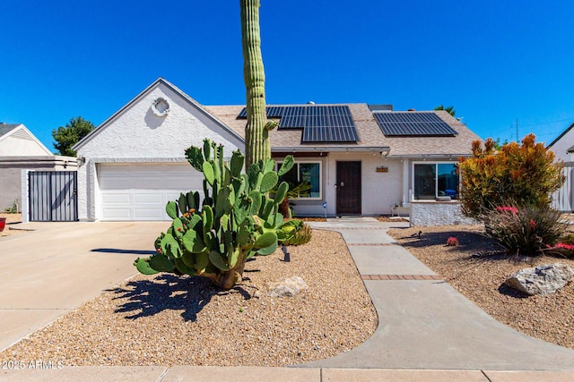 view of front of house featuring a garage, driveway, a shingled roof, and roof mounted solar panels