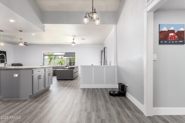kitchen featuring a ceiling fan, open floor plan, wood finished floors, light countertops, and baseboards