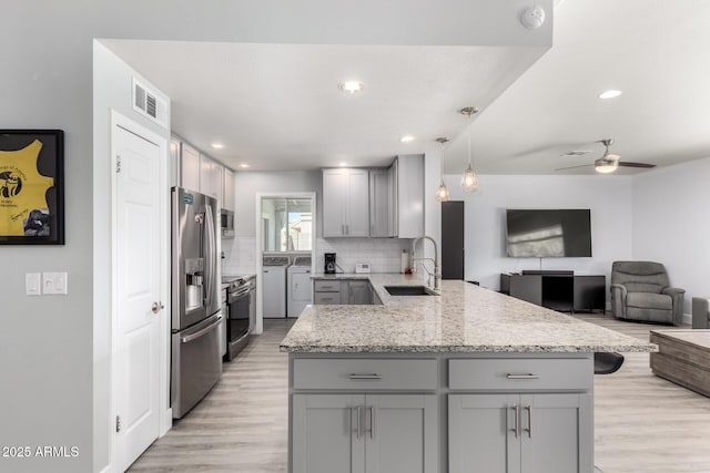 kitchen with gray cabinets, appliances with stainless steel finishes, washing machine and clothes dryer, a sink, and a peninsula