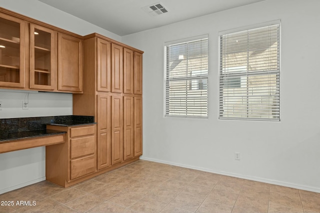 kitchen with dark stone counters, built in desk, and light tile patterned flooring