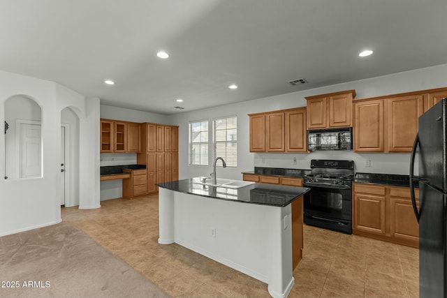 kitchen with sink, light colored carpet, black appliances, and a center island with sink