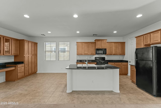 kitchen featuring light tile patterned floors, sink, a center island with sink, and black appliances