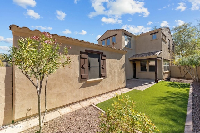 back of house featuring a lawn and a patio