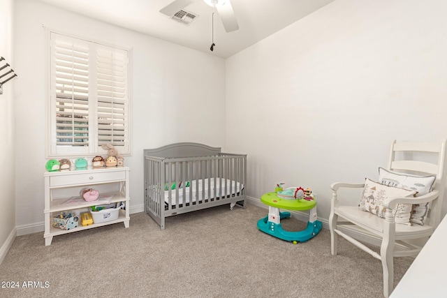 carpeted bedroom with ceiling fan and a nursery area