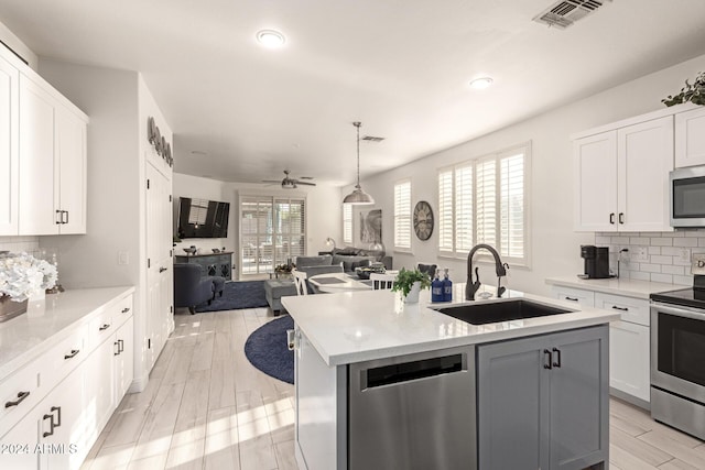 kitchen with a center island with sink, white cabinets, sink, and appliances with stainless steel finishes