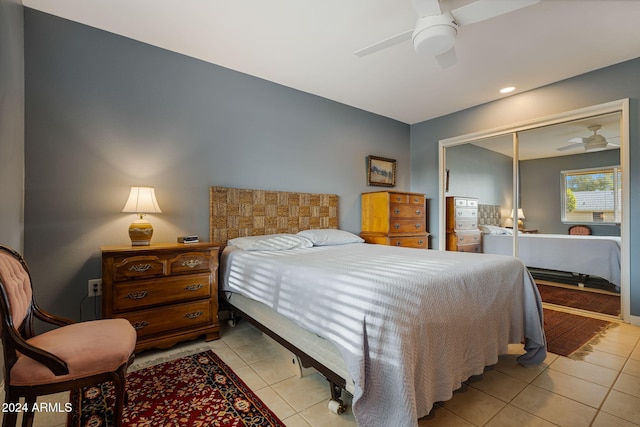 tiled bedroom with ceiling fan and a closet