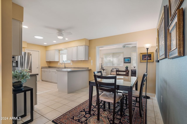 interior space featuring stainless steel fridge, ceiling fan, sink, light tile patterned floors, and white cabinetry