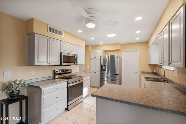 kitchen featuring kitchen peninsula, appliances with stainless steel finishes, ceiling fan, sink, and light tile patterned flooring