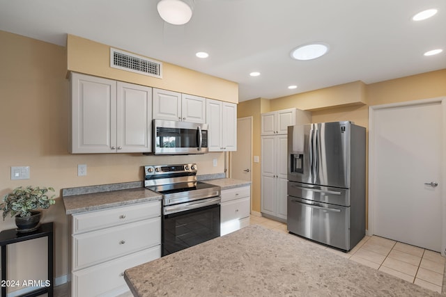 kitchen with white cabinetry, light tile patterned flooring, and appliances with stainless steel finishes