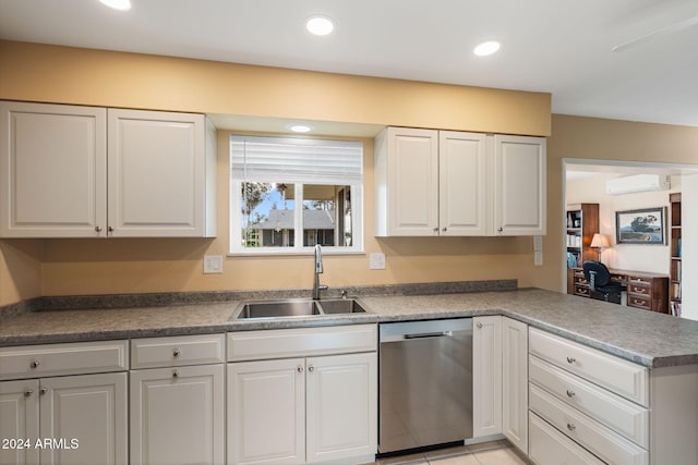 kitchen with a wall mounted AC, white cabinetry, sink, and stainless steel dishwasher