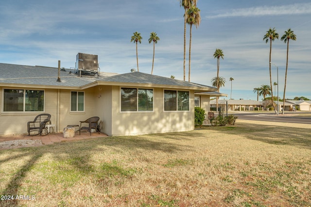 view of side of home with a lawn, a patio area, and central AC