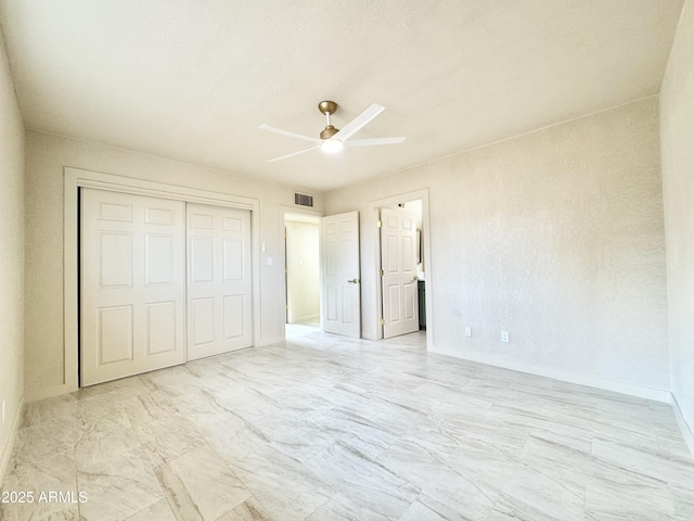 unfurnished bedroom featuring a closet, baseboards, marble finish floor, visible vents, and ceiling fan