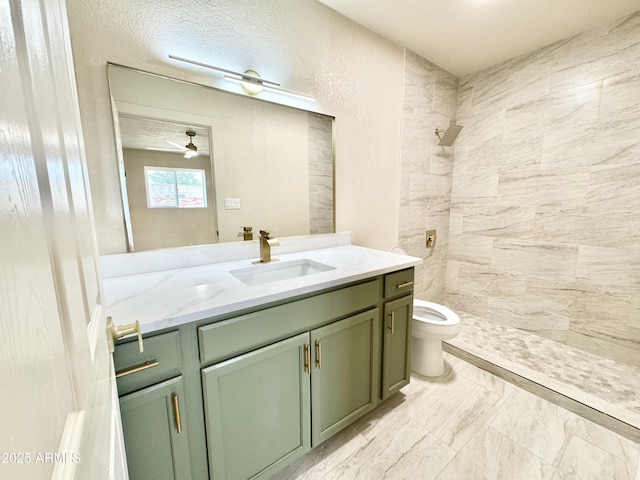 full bathroom featuring toilet, a ceiling fan, a tile shower, marble finish floor, and vanity