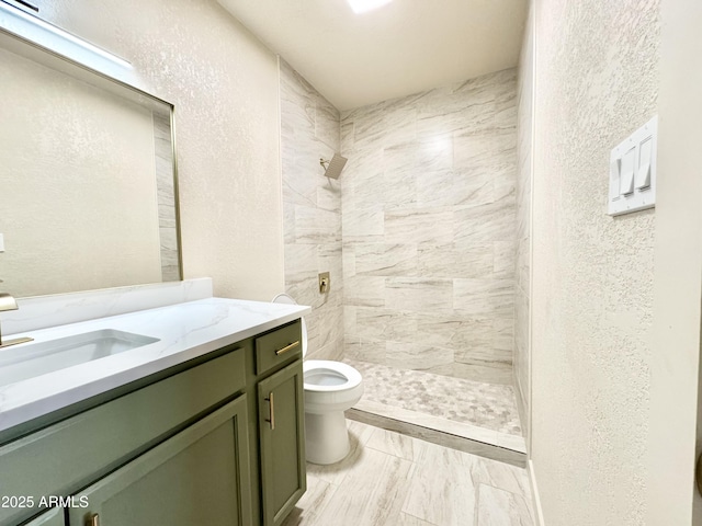 bathroom with toilet, vanity, a stall shower, and a textured wall