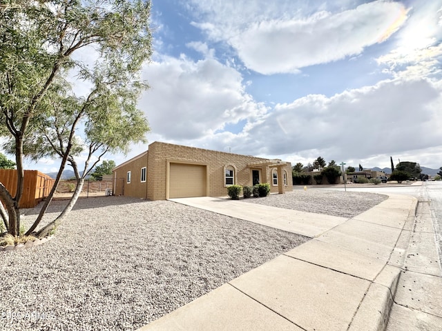view of front facade with driveway, brick siding, a garage, and fence