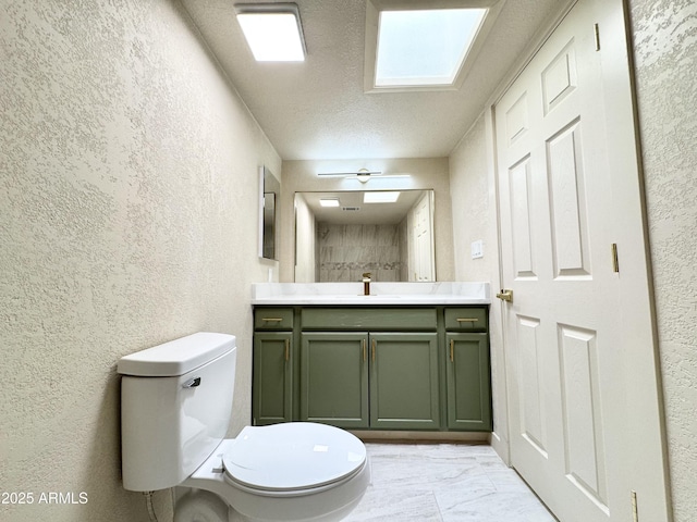 bathroom with a textured ceiling, toilet, vanity, and a textured wall