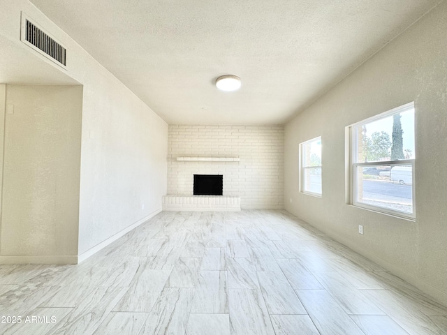unfurnished living room with a textured ceiling, visible vents, and a fireplace